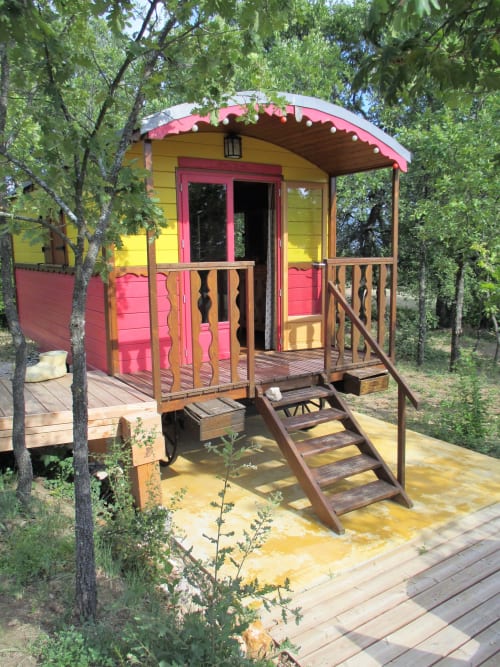 Caravane Airstream colorée au Mas du Fort à Gargas, façade rose et jaune, terrasse en bois et jardin