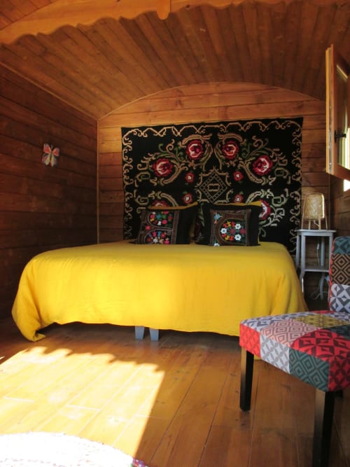Chambre douillet du gîte en bois avec literie jaune et tête de lit noire décorée au Mas du Fort, Gargas