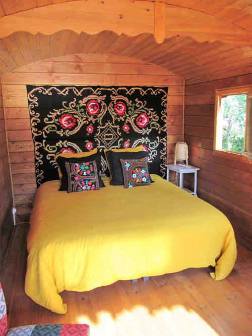 Chambre cosy du Mas du Fort avec literie jaune, tête de lit ornementale noire et coussins colorés à Gargas
