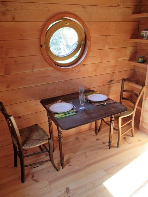 Salle à manger chaleureuse du Mas du Fort avec fenêtre hublot ronde et table dressée pour deux, Gargas