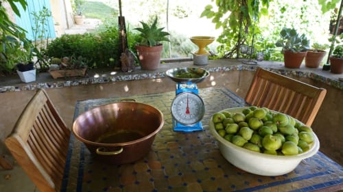 Comptoir de cuisine rustique au Mas du Fort avec pommes vertes fraîches, balance en laiton et plantes en pot à Gargas