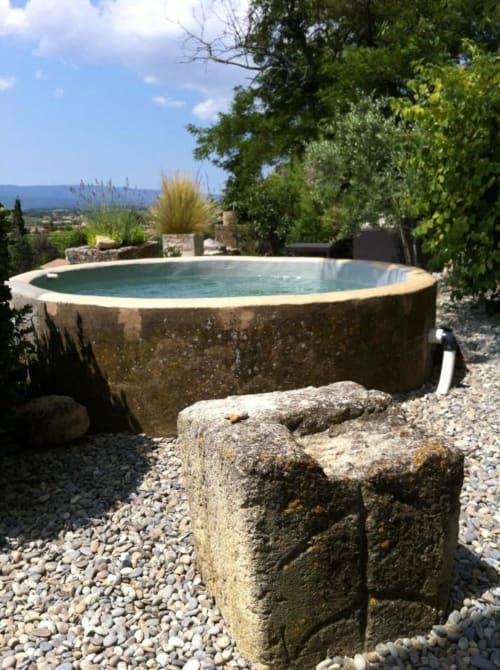 Piscine en pierre rustique du Mas du Fort aux eaux turquoise, entourée de lavandes et de paysages provençaux