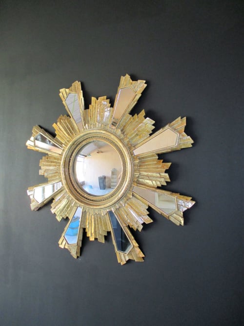 Miroir en forme de soleil doré sur mur sombre au Mas du Fort, Gargas, France