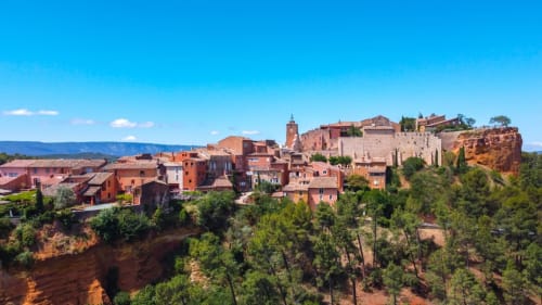Le Mas du Fort B&B à Gargas, France : village ocre perché sur des falaises rouges avec bâtiments en pierre et clocher sous ciel bleu