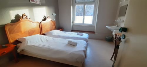 Chambre lumineuse à la Résidence Soansa du Gérardmer avec deux lits, tête de lit en bois, vue sur le jardin et équipements modernes