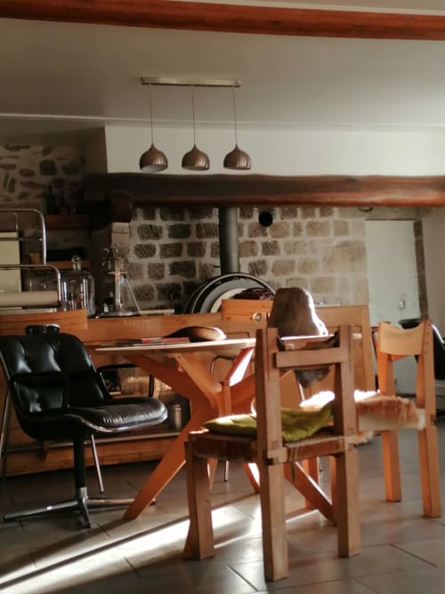 Furanelle B&B dining area in Saint Etienne with wooden table, chairs, stone walls, and pendant lighting