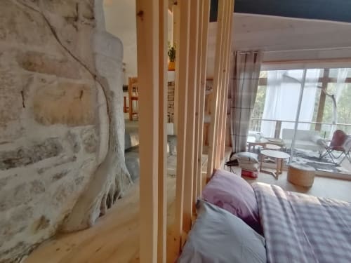 Chambre de la Furanelle B&B à Saint-Étienne avec poutres en bois, murs en pierre et vue montagne depuis le balcon