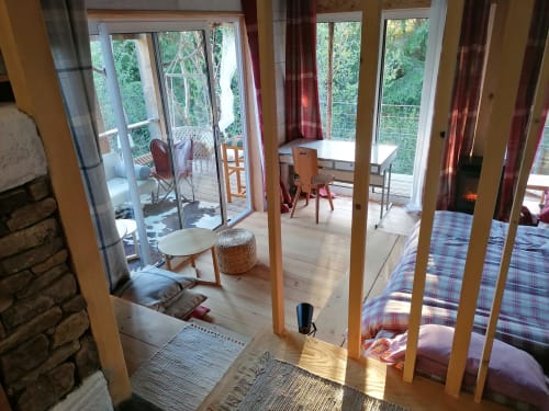 Chambre spacieuse avec piliers en bois, literie à carreaux et portes vitrées ouvrant sur balcon avec vue montagne à Furanelle B&B