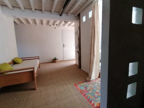 Chambre spacieuse à la BnB Furanelle à Saint Etienne avec lit en bois, plafond à poutres et tapis coloré