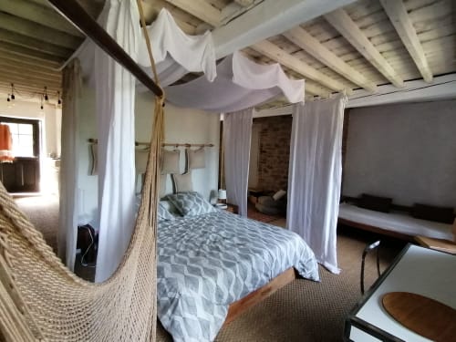Chambre spacieuse avec lit à baldaquin, voilages blancs, poutres apparentes et vue sur les montagnes à la Furanelle B&B