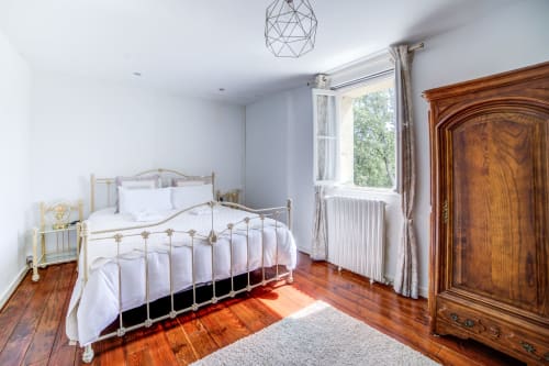 Chambre élégante du Manoir Le Coutureau avec lit en laiton, parquets et vue sur le jardin