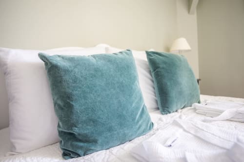 Lit confortable aux coussins bleus-verts et oreillers blancs au Manoir Le Coutureau, chambre d'hôtes française