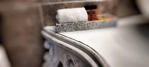 Équipements salle de bains au Manoir Le Coutureau : serviette blanche roulée dans un support en pierre avec articles de toilette