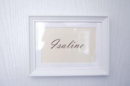 Panneau nominatif encadré « Isaline » sur mur blanc texturé à la Maison d'hôtes Manoir Le Coutureau