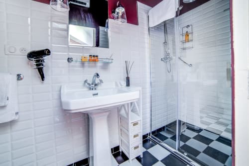 Salle de bain moderne du Manoir Le Coutureau avec carrelage métro blanc, lavabo sur colonne, cabine de douche en verre et décor noir et blanc