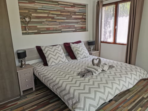 Modern bedroom at Domaine à l'Aise with chevron patterned bedding, wood accent wall, and French doors to pool view