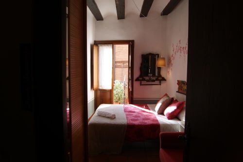 Chambre Santo Domingo de la Casa Peregrinando à Navarrete avec literie rouge, poutres en bois et vue sur la ville