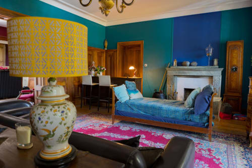 The lounge of the Le Clos d'Azel guest house features colorful walls that create a warm atmosphere with its ornamental fireplace and period furniture.