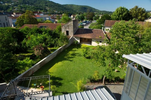Vue aérienne du jardin fleuri de La Maison De Siloe à Villefranche de Rouergue avec toits en terre cuite