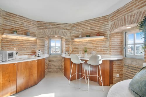 Luxury apartment at La Tour Du Capitole Toulouse with brick walls, wooden cabinetry, bar seating, and views of the city