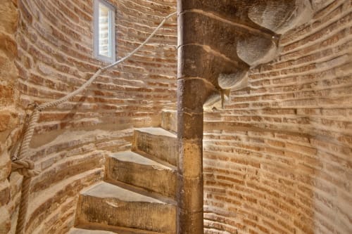 Wooden spiral staircase in historic brick tower at La Tour Du Capitole, Toulouse landmark apartment.