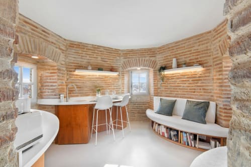 Interno moderno di appartamento con pareti curve in mattoni, rivestimento in legno, isola cucina e bar presso La Tour Du Capitole Toulouse
