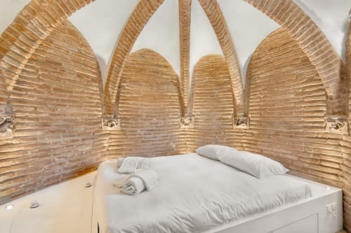 Camera accogliente a La Tour Du Capitole a Tolosa con letto bianco, cuscini e testata decorativa in palma intrecciata