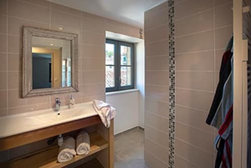 Salle de bain moderne du gîte La Maison De Siloe avec lavabo, miroir, fenêtre et porte-serviettes à Villefranche de Rouergue