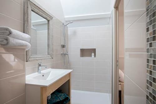 Salle de bain moderne du gîte La Maison De Siloe à Villefranche de Rouergue, avec douche à l'italienne, vasque et miroir.