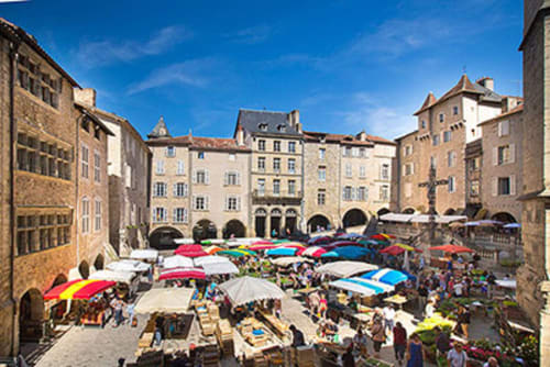 Place du marché colorée à La Maison De Siloe à Villefranche de Rouergue avec ses parasols éclatants et son architecture médiévale