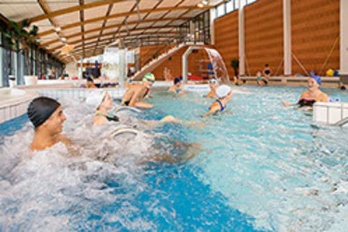 Piscine intérieure de La Maison De Siloe avec baigneurs et équipements de jeux aquatiques à Villefranche de Rouergue