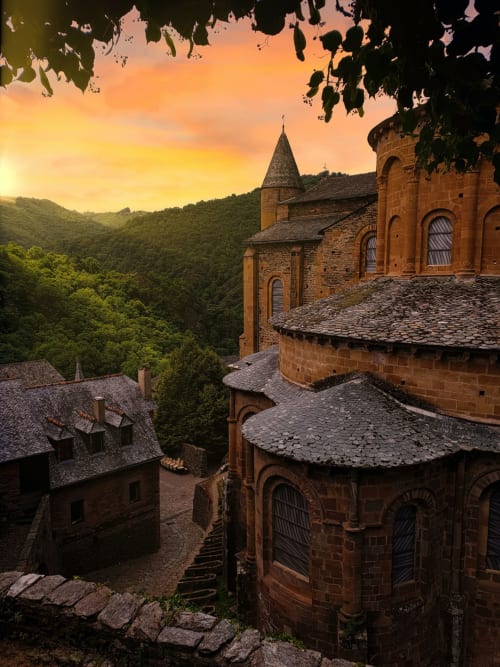 Église médiévale en pierre avec clocher au coucher de soleil dominant les vallées verdoyantes, La Maison De Siloe à Villefranche de Rouergue