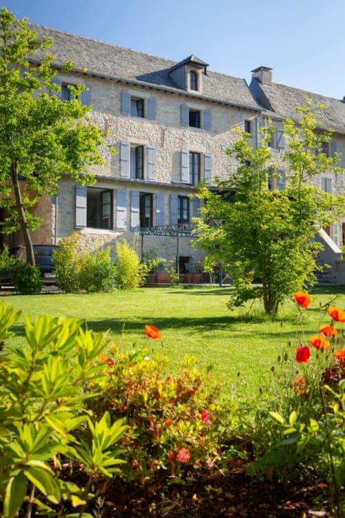 La Maison de Siloe, manoir en pierre avec jardins soignés et tulipes rouges à Villefranche-de-Rouergue