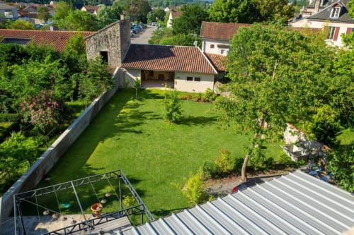 Vue aérienne du jardin luxuriant de La Maison De Siloe à Villefranche de Rouergue avec maisons en pierre