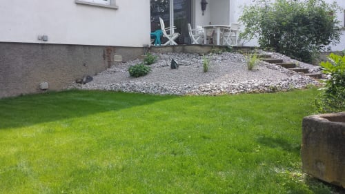 Geräumiger Garten mit gepflegtem Rasen, Kiesterrasse und Sitzbereich im La Tour De L'ill in Straßburg
