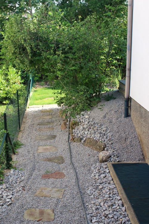 Schmaler Gartenweg mit Trittsteinen und Kies im La Tour De L'ill Cottage in Straßburg, gesäumt von üppigem Grün