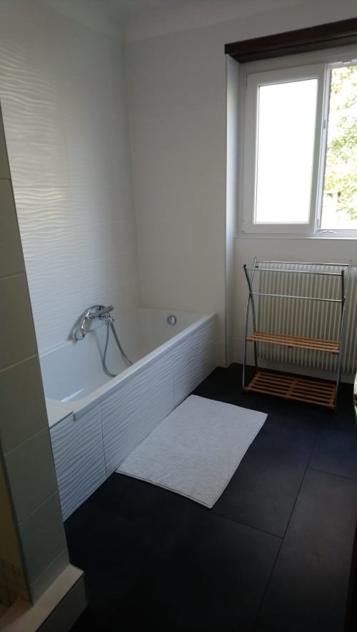 Modernes Badezimmer im Ferienhaus La Tour De L'ill in Straßburg mit Badewanne, weißen Kacheln und Fensterblick