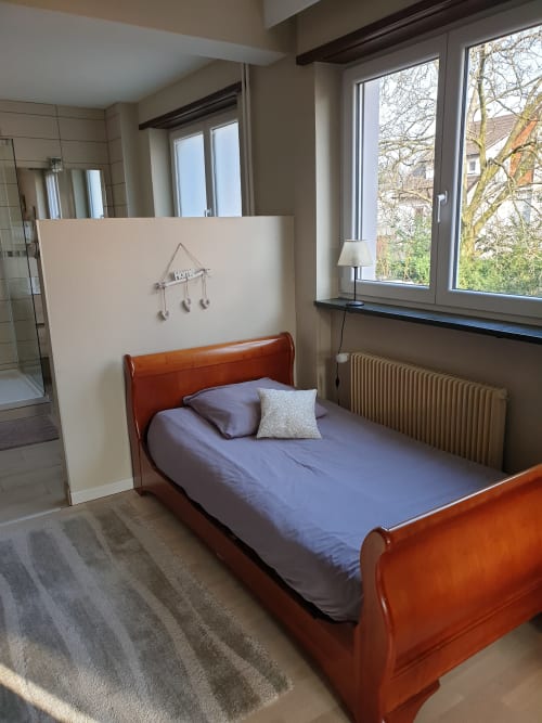 Gemütliches Schlafzimmer in La Tour De L'ill, Strasbourg mit Holzschlitten-Bett, weißem Raumteiler, Heizkörper und Flussblick