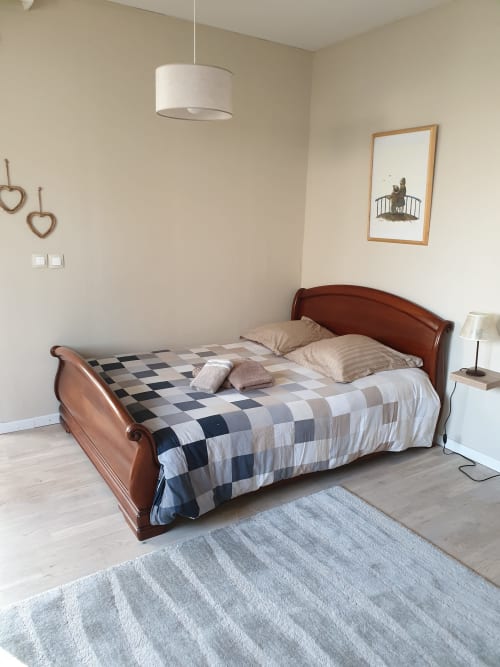Schlafzimmer im Cottage La Tour De L'ill in Straßburg mit hölzernem Schlittenbett, karierter Bettwäsche, Pendelleuchte und Rahmen