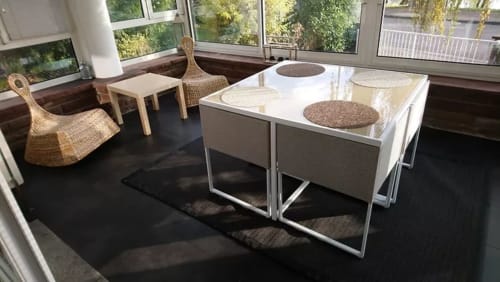 Lounge moderne du B&B La Tour De L'ill à Strasbourg avec fauteuils en rotin, tables blanches et sol sombre.