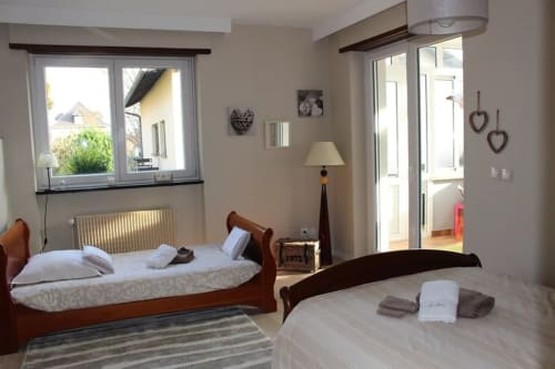 Chambre lumineuse à La Tour De L'ill B&B à Strasbourg avec deux lits en bois, grandes fenêtres et équipements modernes