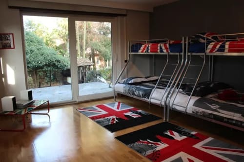 Chambre lits superposés moderne à La Tour De L'ill BnB Strasbourg avec décor Union Jack, portes vitrées donnant sur patio jardin et bois poli