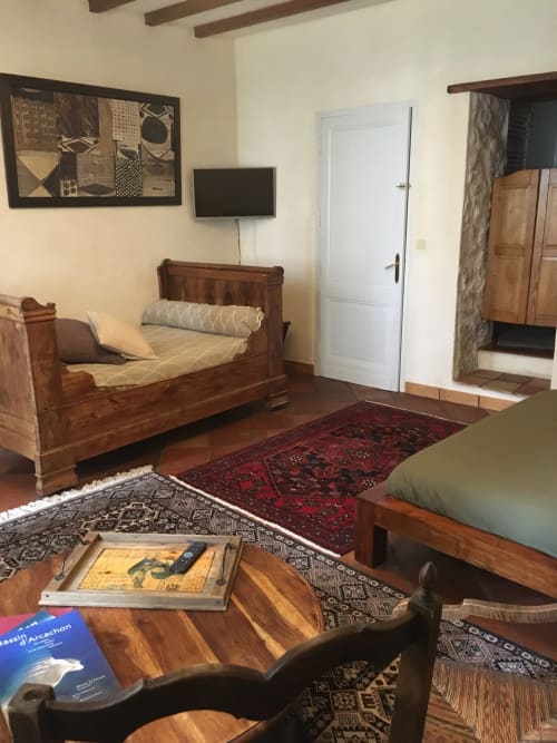 Chambre rustique à Sous Les Marronniers avec lit en bois, télévision, cheminée et mobilier d'époque à Petit Palais Cornemps