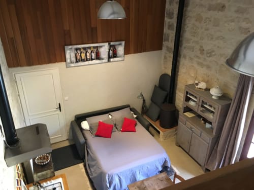 Chambre moderne du gîte Sous Les Marronniers à Petit Palais Cornemps avec lit, oreillers rouges, coin salon et boiseries