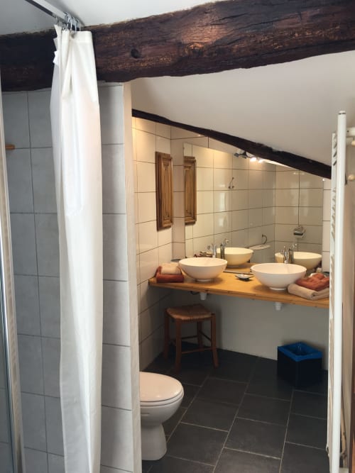 Salle de bains du gîte Sous Les Marronniers à Petit Palais Cornemps avec trois vasques, carrelage foncé et style rustique