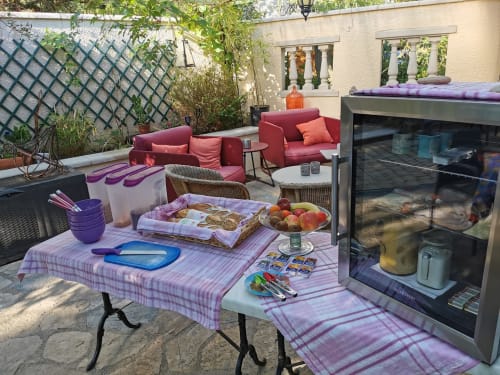 Charmante terrasse du Domaine à l'Aise à Saint-Pargoire avec table mauve, mets gourmands, sièges bordeaux et vues sur le jardin.