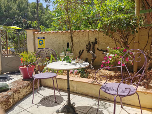Charmante terrasse du Domaine à l'Aise à Saint-Pargoire avec chaises bistrot violettes, table blanche et verres de vin