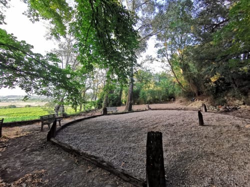 Allée de gravier ombragée bordée d'arbres à Domaine à l'Aise avec bancs, champs verts et vue sur la campagne à Saint-Pargoire