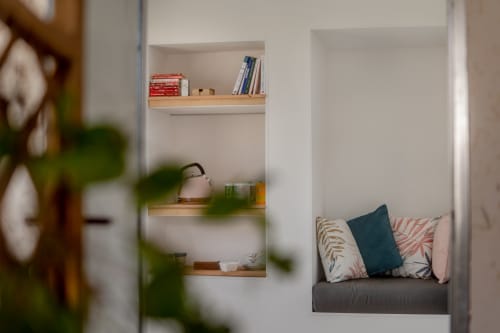Cozy alcove at Le Pignié B&B with wooden shelves, books, kettle, and cushioned seating nook in Lescure-d'Albigeois