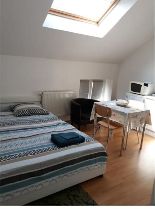 Chambre lumineuse sous les combles à la Résidence Mantekila à Marcinelle avec puits de lumière, deux lits, bureau et micro-ondes